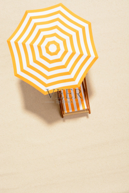 暑假的概念。顶视图在阳光躺椅下的一把伞在沙滩上正版图片素材