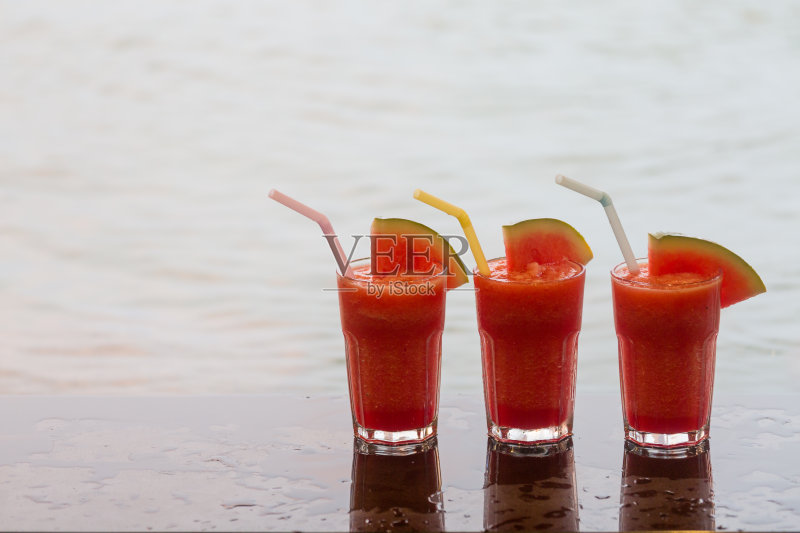 背景水果汁-三杯西瓜汁放在泳池边。正版图片素材