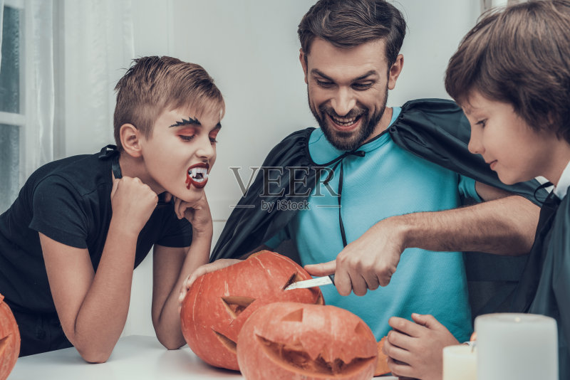 男人和孩子们在雕刻南瓜正版图片素材
