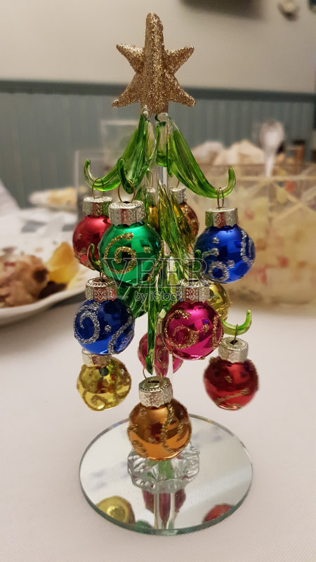 节日餐桌上摆放着微型玻璃圣诞树,上面装饰着彩色的玻璃球形状的圣诞装饰品,上面装饰着金色的闪光卷发。新年庆祝属性正版图片素材