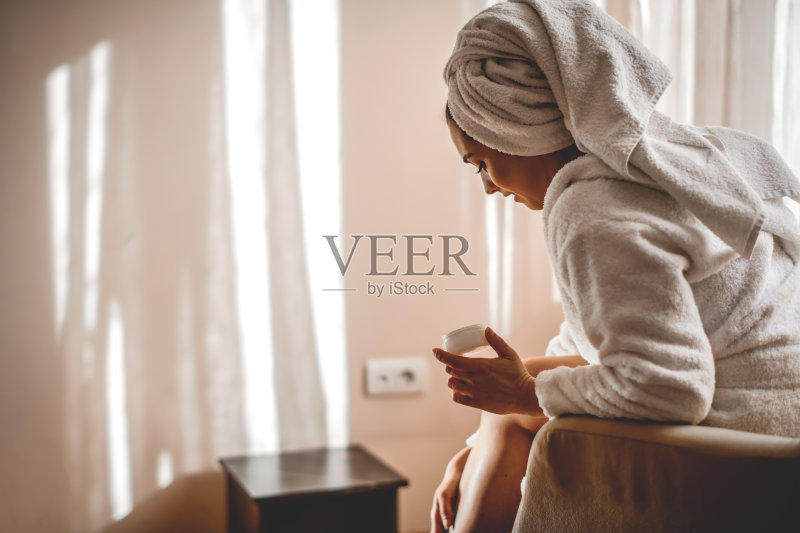 在腿上涂保湿霜的女人正版图片素材