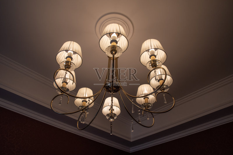 复古风格的吊灯与金色发光的灯罩和闪闪发光的水晶吊坠。天花板上的古董灯的特写。豪华室内照明概念。正版图片素材