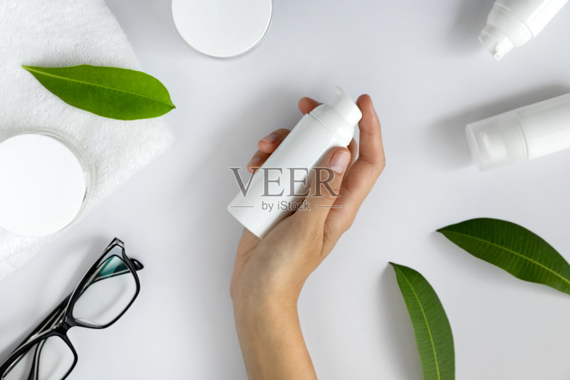 女人的手用化妆品的润肤霜放在白色的桌子上正版图片素材