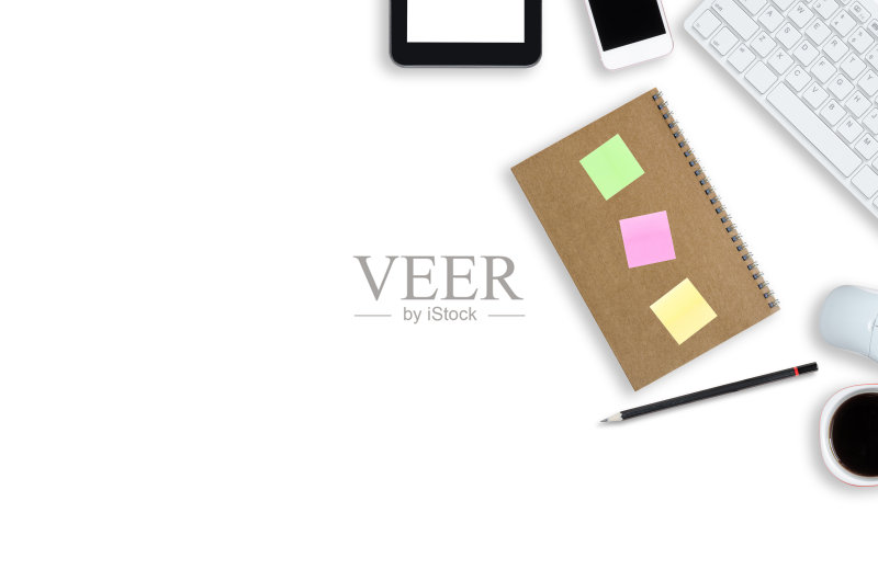 顶视图白色桌子办公室工作。办公台面上方设计平躺着笔记本电脑键盘、咖啡杯、鼠标、智能手机、平板电脑和文具配件供应。正版图片素材