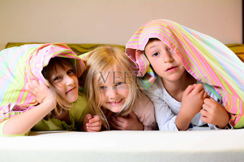 快乐的孩子们看着毯子在镜头里微笑。正版图片素材