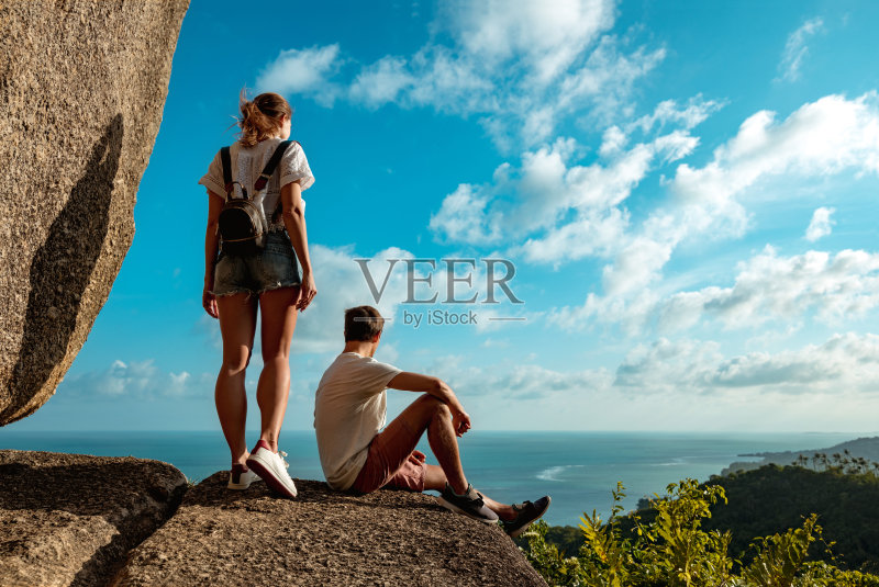 一对美丽的夫妇站在大海和丛林的大岩石上正版图片素材