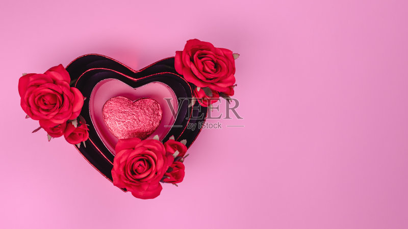 红色美丽的玫瑰在心形礼品盒与红色的心在粉红色的背景。正版图片素材