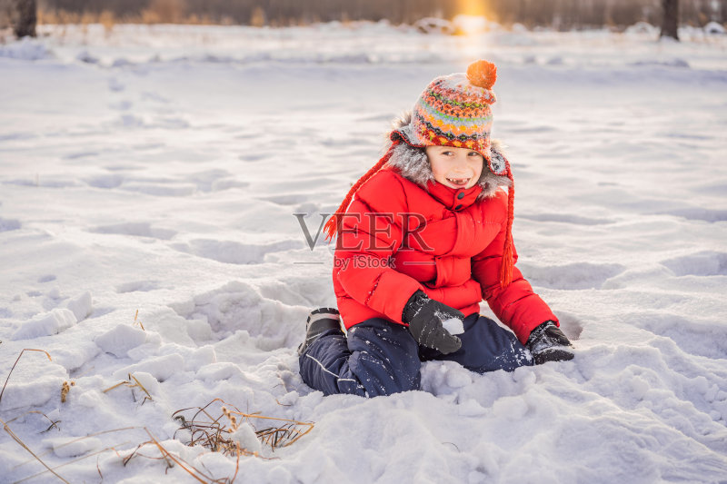 在雪地里玩耍的小男孩照片摄影图片