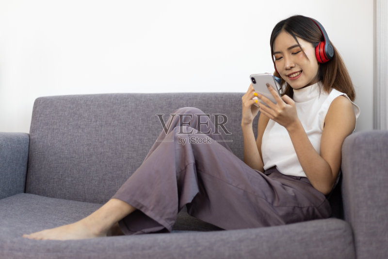 亚洲女性坐在客厅的沙发上,用手机听音乐的居家生活方式特写照片摄影图片