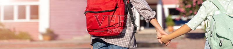 孩子们手牵着手背着书包回学校特写,超宽banner,有文案空间照片摄影图片