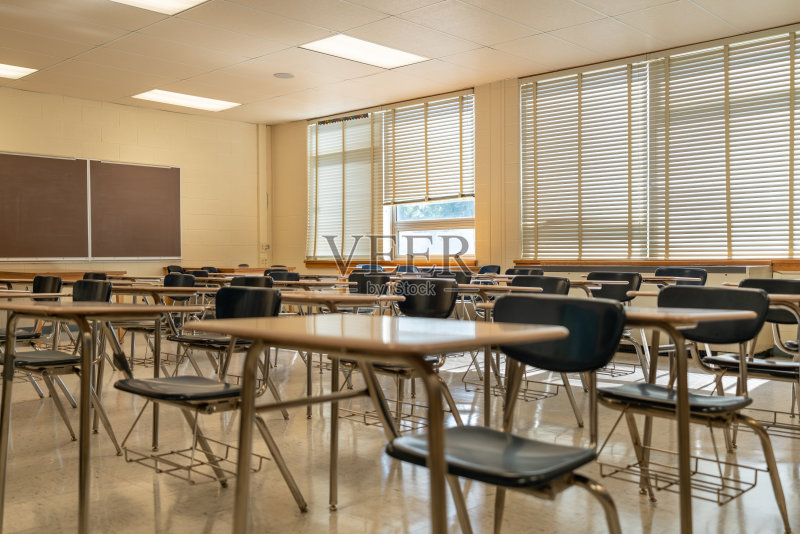 一个空的无特征的美国高中教室的例子,有桌子,窗户和黑板。正版图片素材
