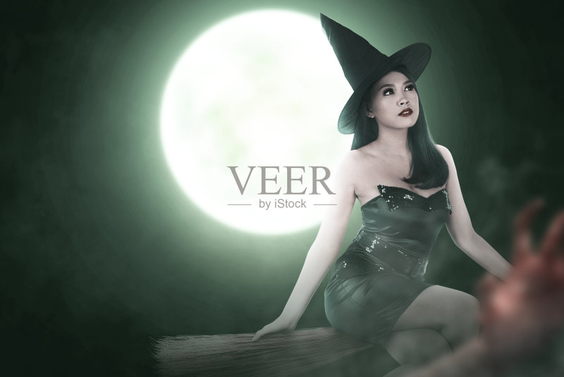 戴着帽子在魔法扫帚上飞舞的亚洲女女巫正版图片素材