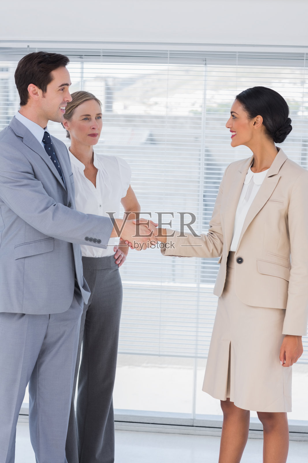 商务人士在明亮的办公室握手照片摄影图片