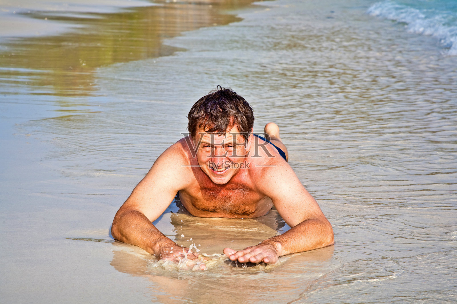 穿着泳衣的男人躺在海滩上照片摄影图片