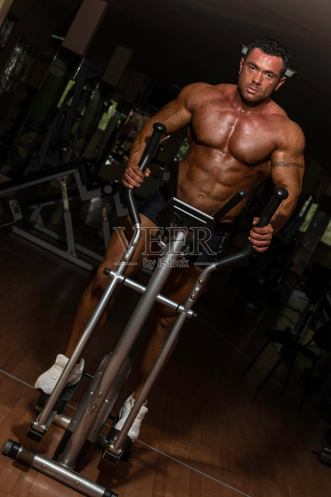 男性健美运动员使用椭圆机照片摄影图片