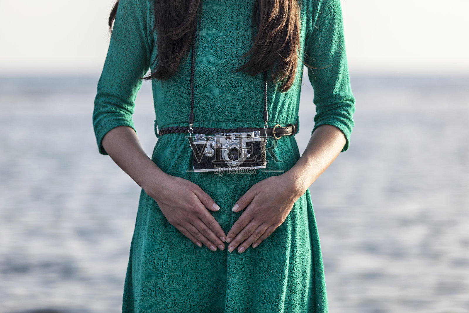 海边有个带着复古相机的黑发女孩照片摄影图片