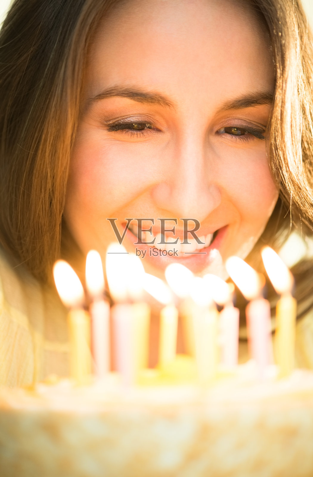 女人看着点着蜡烛的蛋糕照片摄影图片