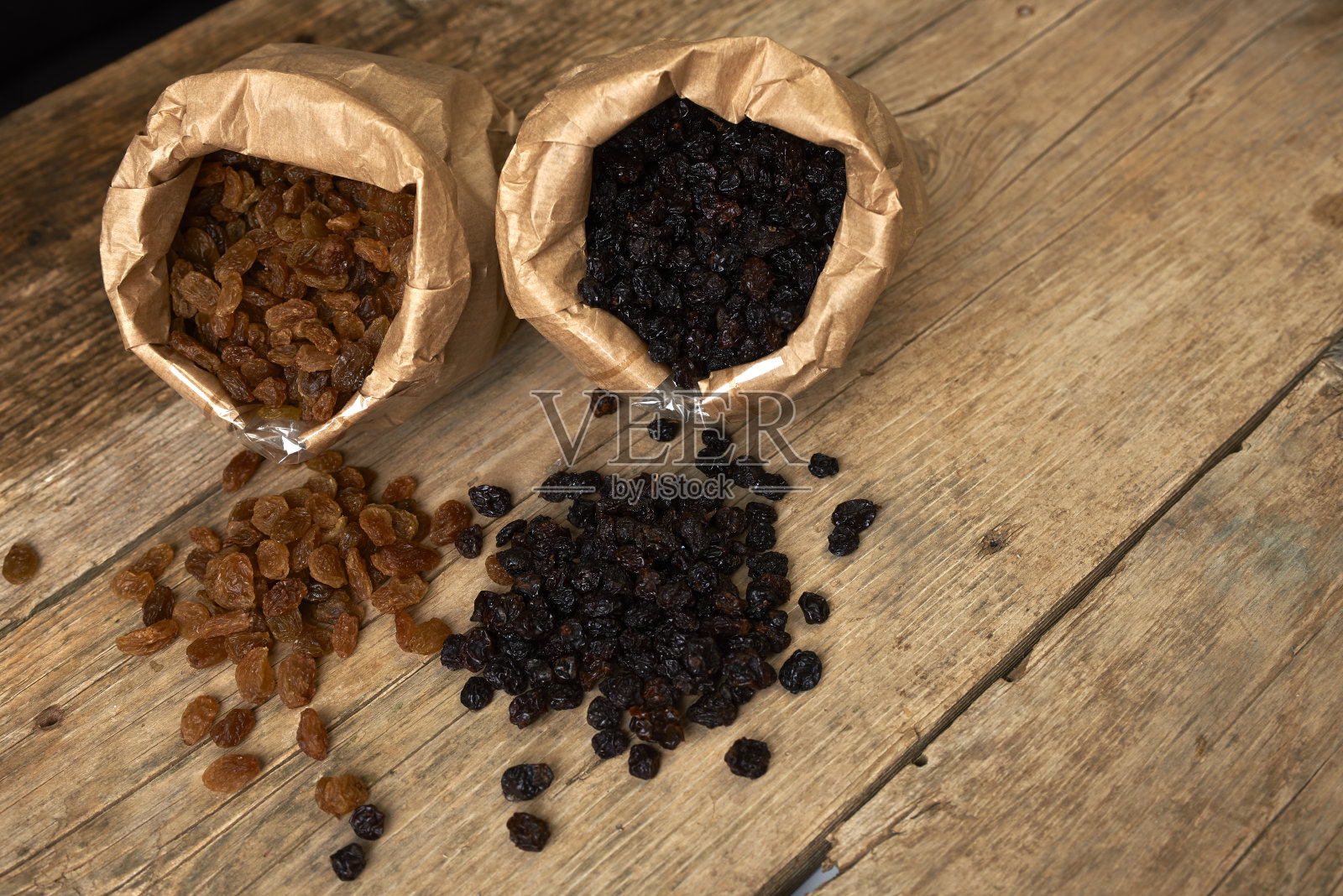 金色和黑色的葡萄干装在纸袋里照片摄影图片