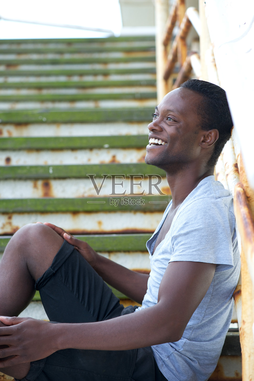 一个黑人坐在外面的楼梯上大笑照片摄影图片