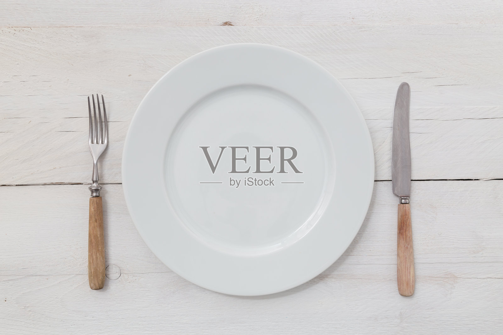 白色的盘子和银器放在浅色的木头上照片摄影图片