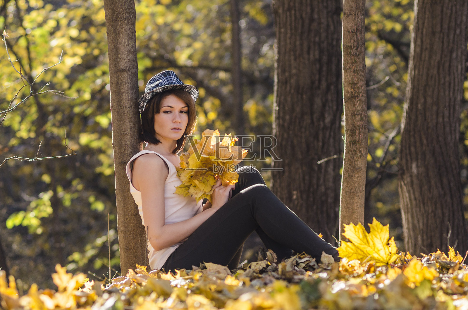 秋天的森林里，年轻的姑娘拿着一束树叶照片摄影图片