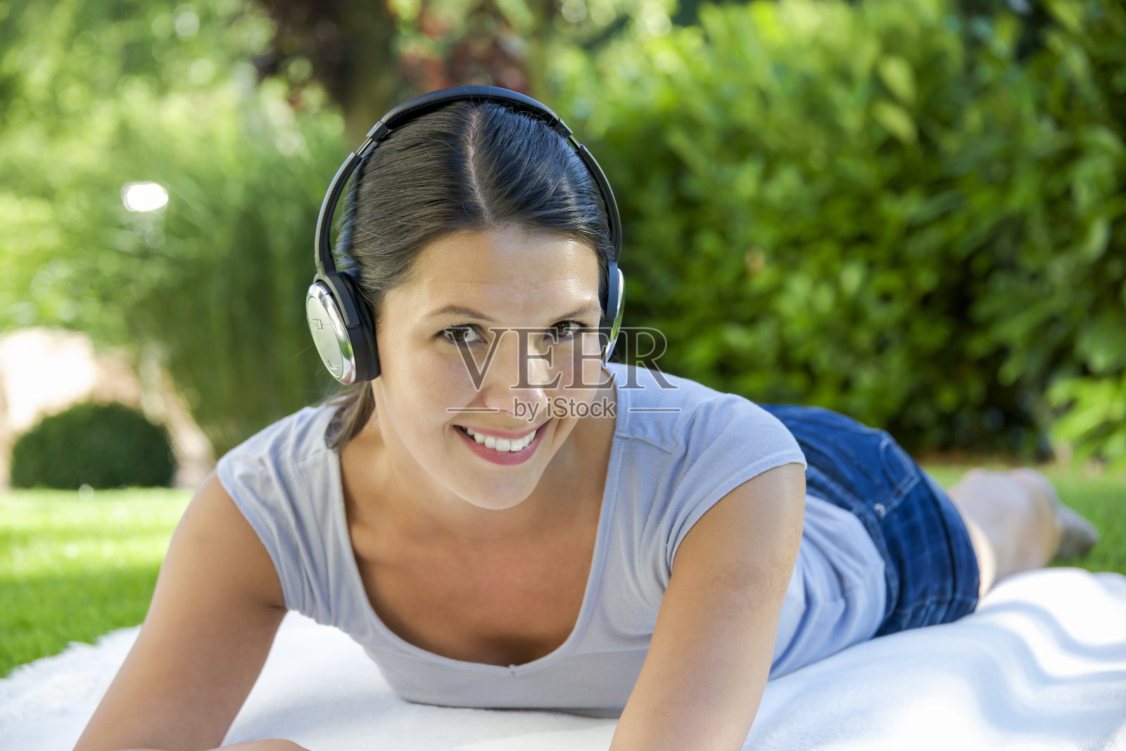 女人躺在毯子上，戴着耳机照片摄影图片
