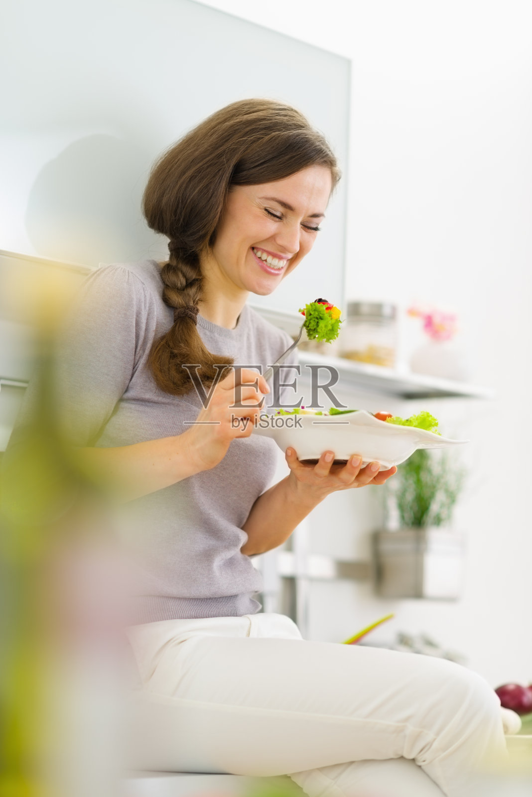 快乐的年轻女子在现代厨房吃新鲜的沙拉照片摄影图片