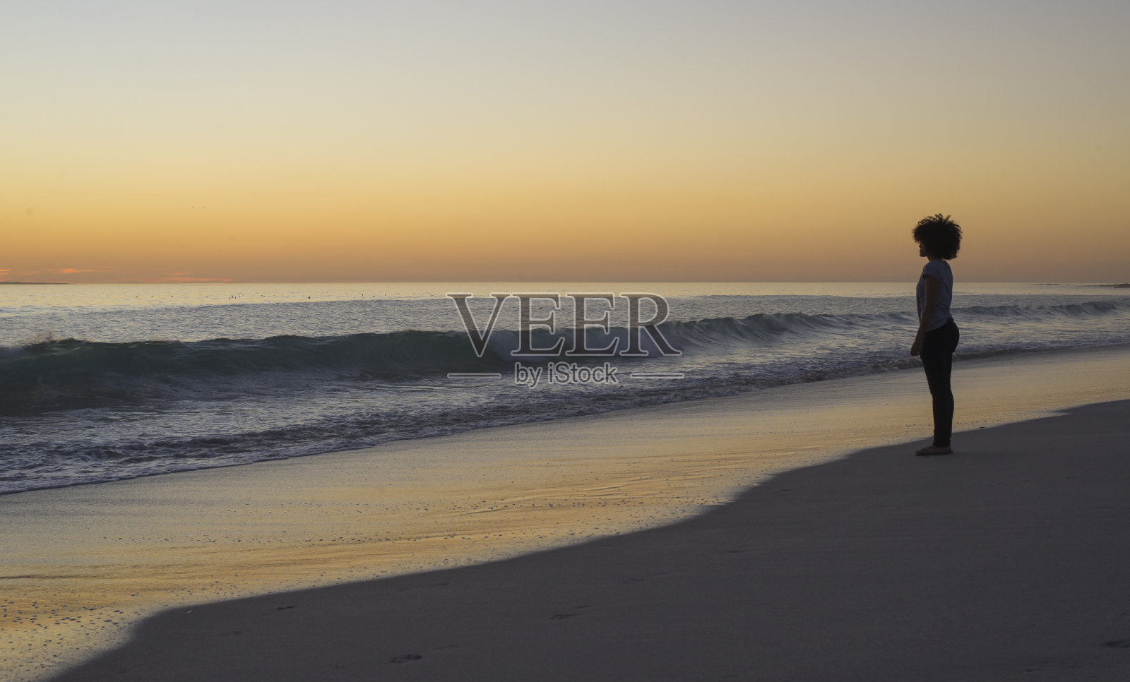 沙滩上凝视夕阳的女人照片摄影图片