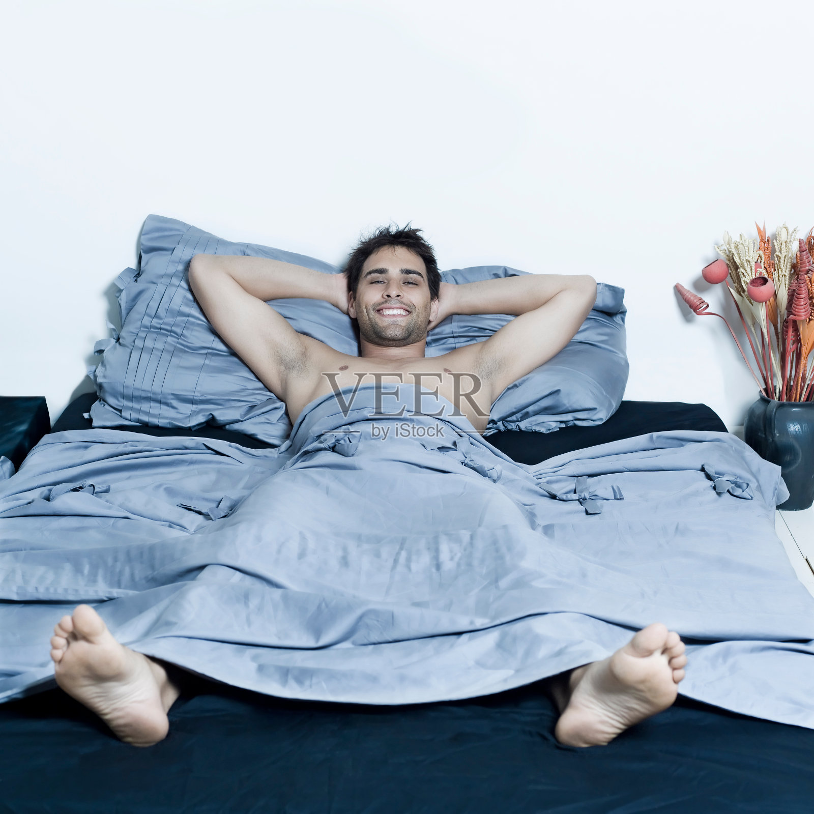 英俊的年轻人躺在床上，微笑着照片摄影图片