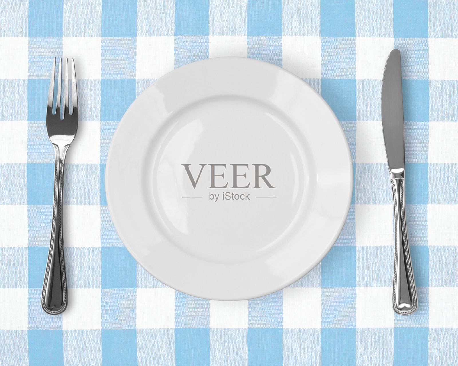 刀，白盘子和叉子放在蓝格子桌布上照片摄影图片