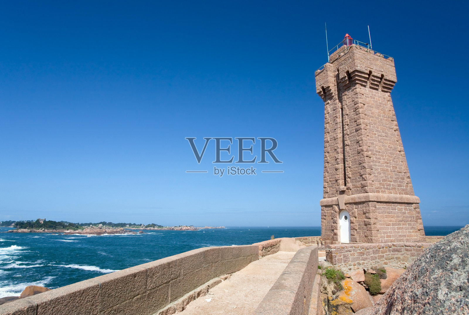 法国布列塔尼粉红色花岗岩海岸岩石中的灯塔照片摄影图片