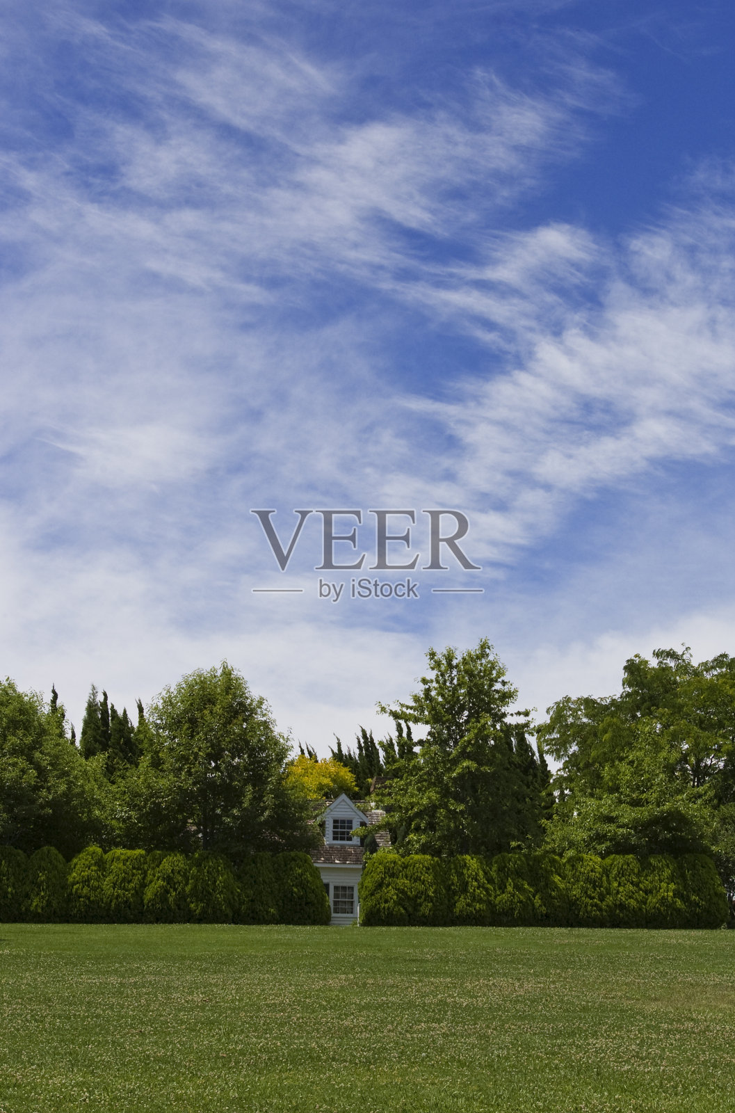 房子在有大天空的树篱后面照片摄影图片