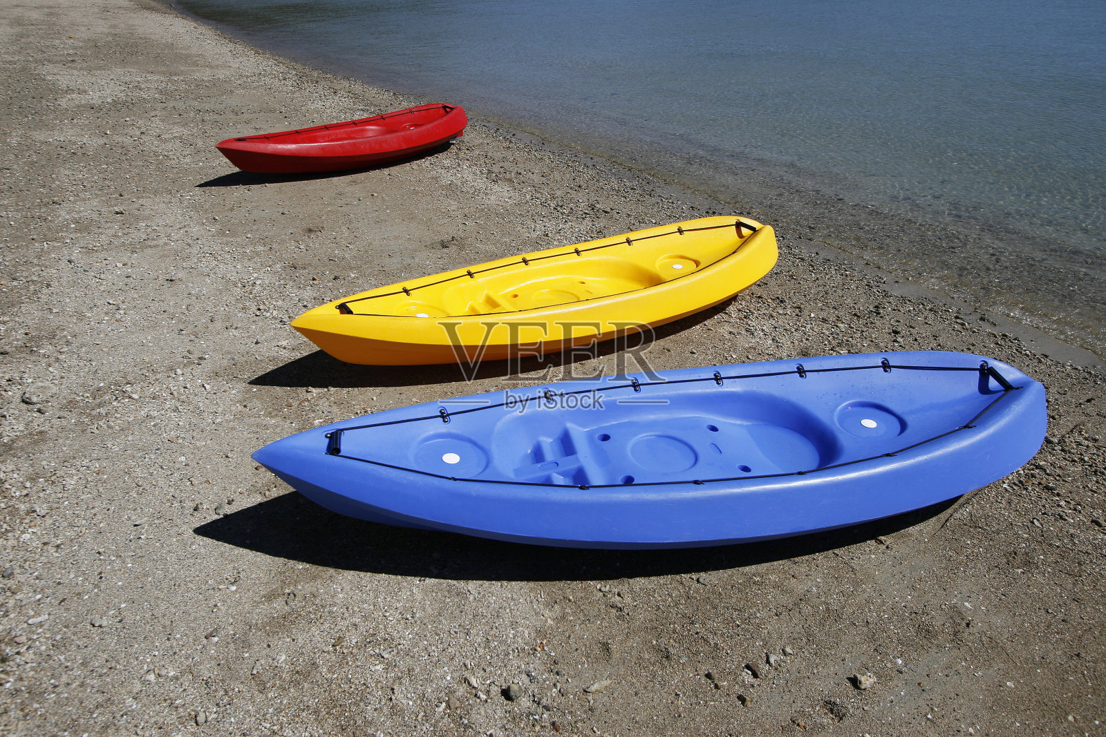 绿松石色的海水边，沙滩上五颜六色的皮艇照片摄影图片