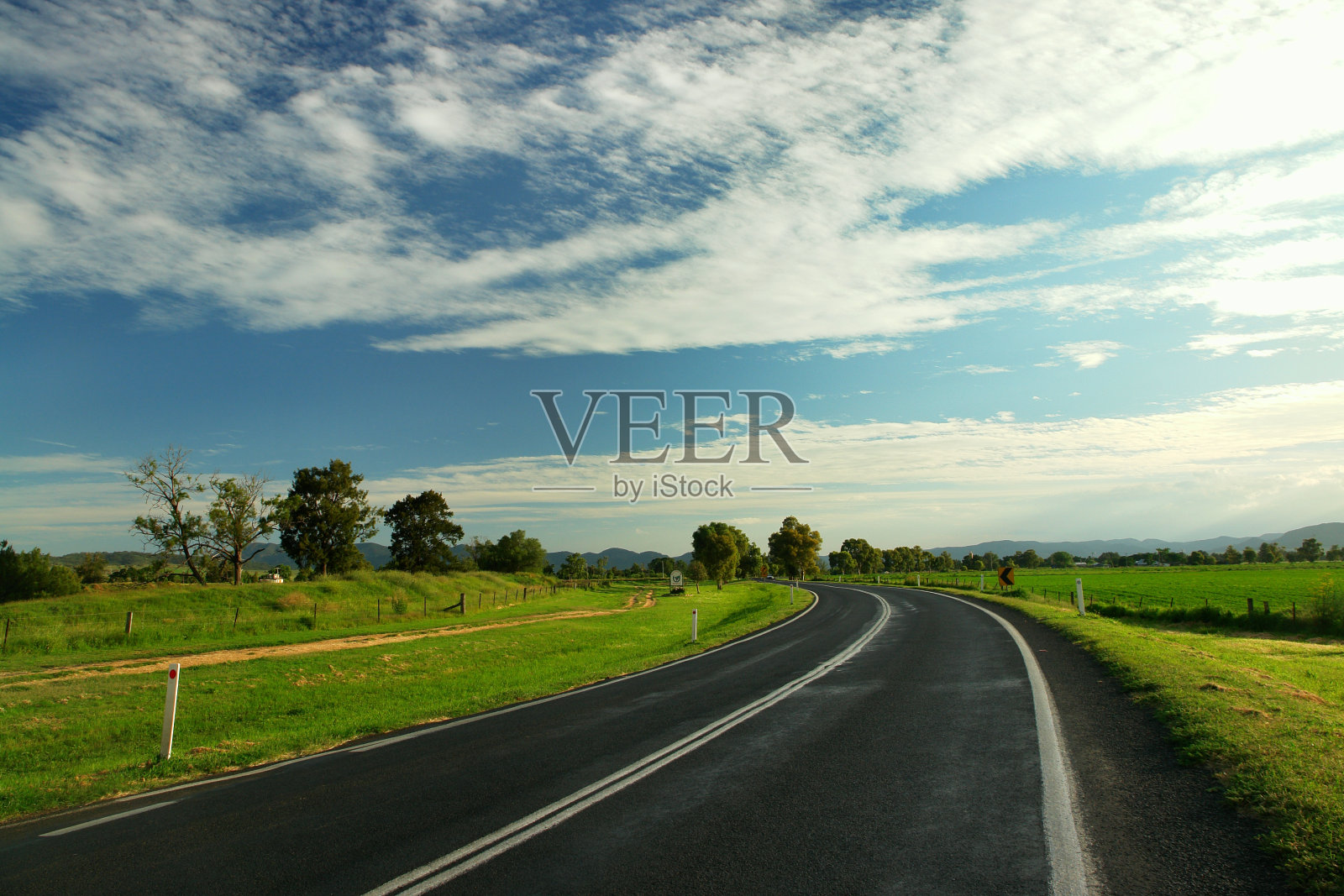 双车道铺装公路上的草地和蓝天照片摄影图片