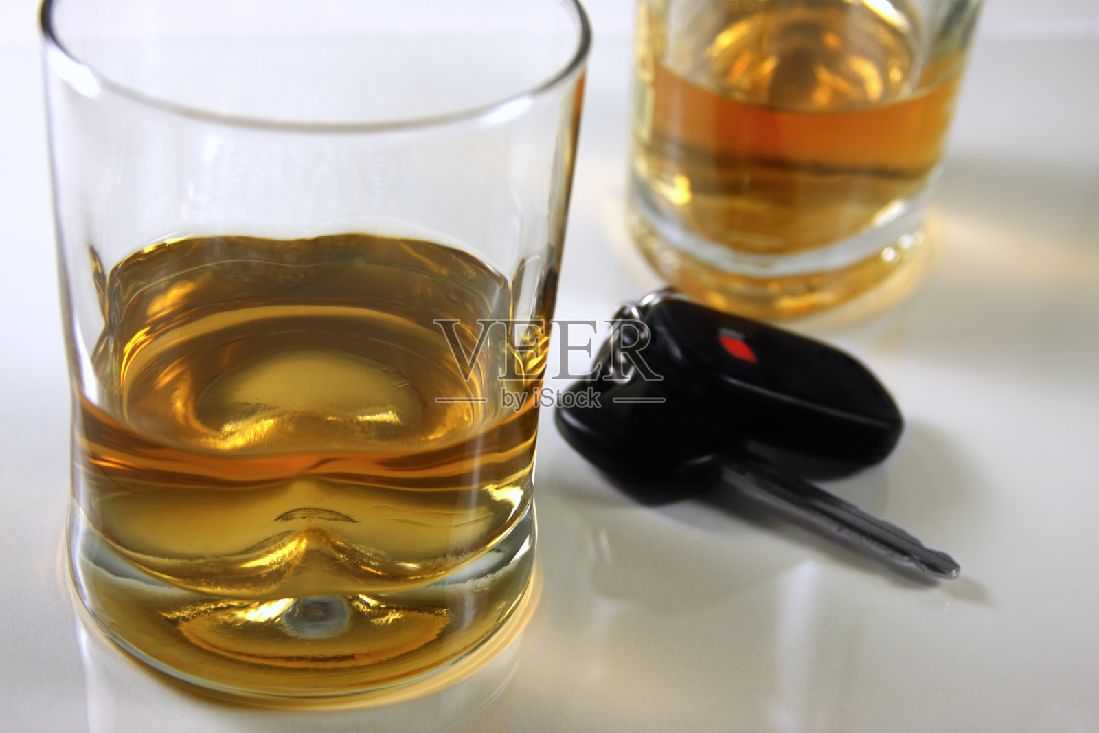 车钥匙放在一张白色的桌子上，旁边放着一杯酒照片摄影图片