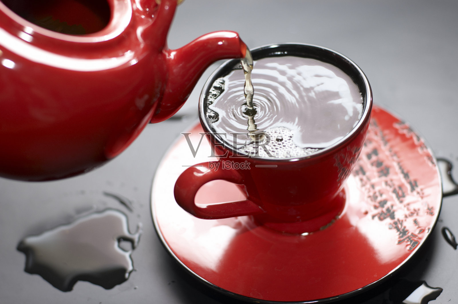 把茶倒进红色的杯子里照片摄影图片