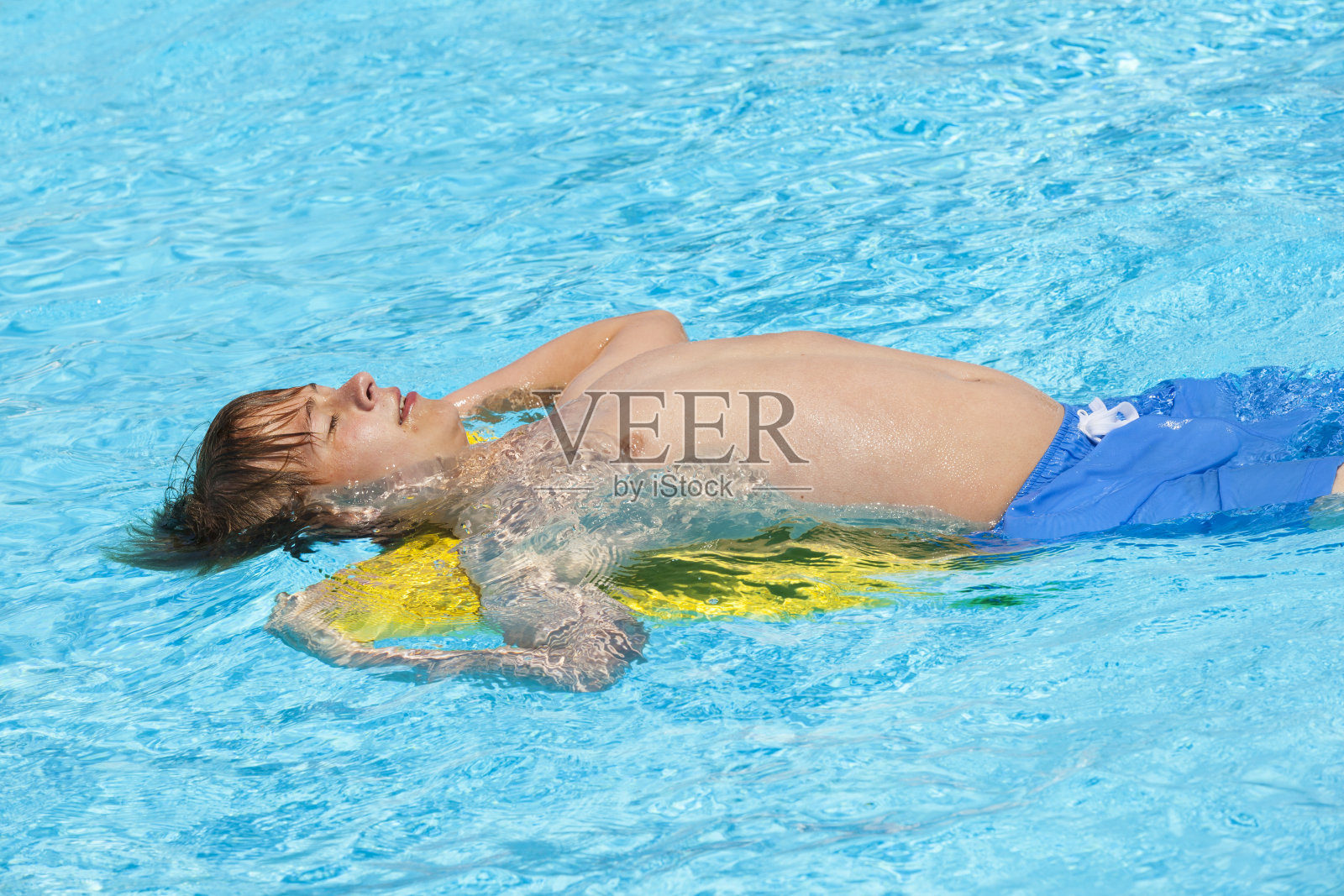 男孩在游泳池里游泳照片摄影图片