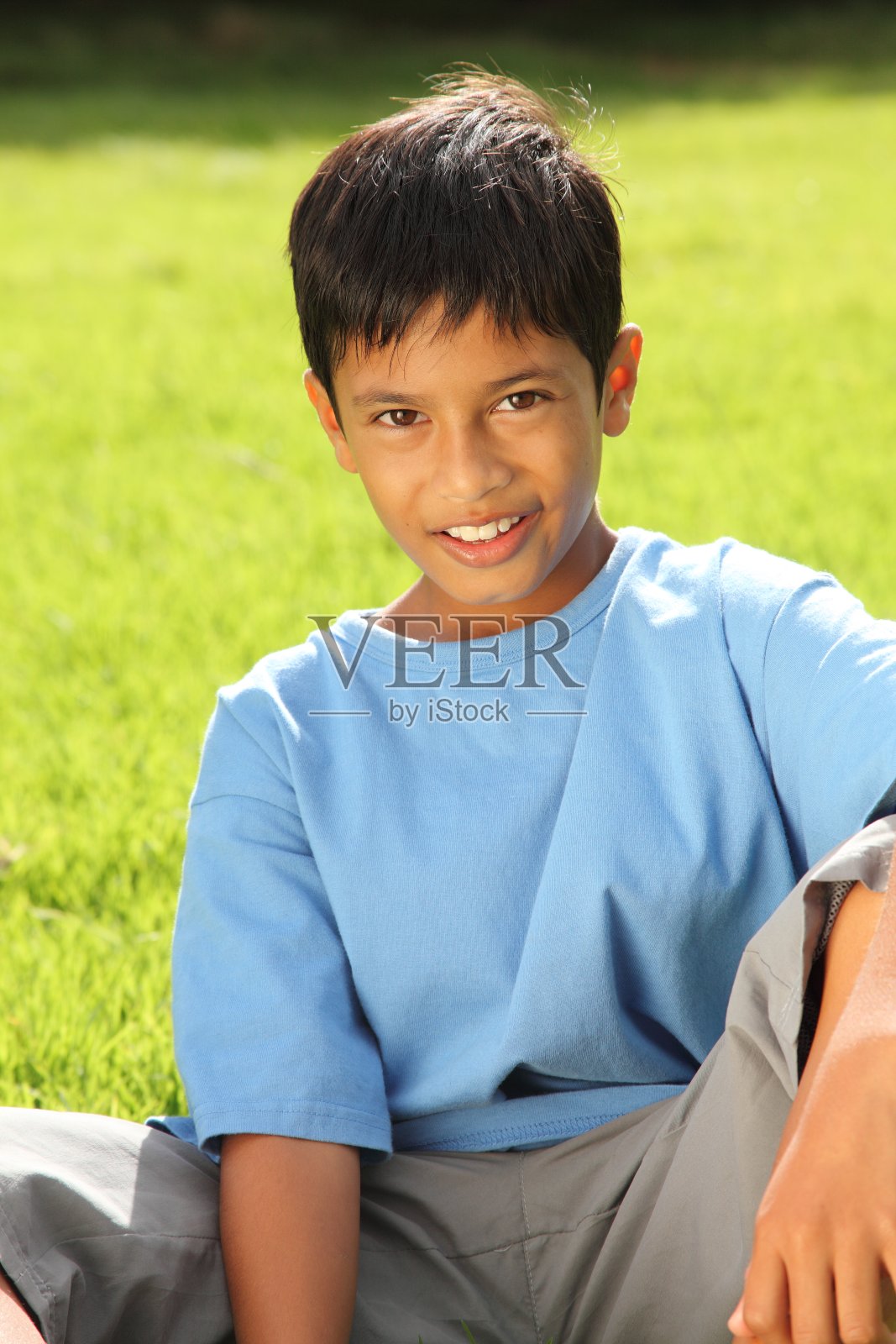 男孩10坐在美丽明亮的阳光下的草地上照片摄影图片