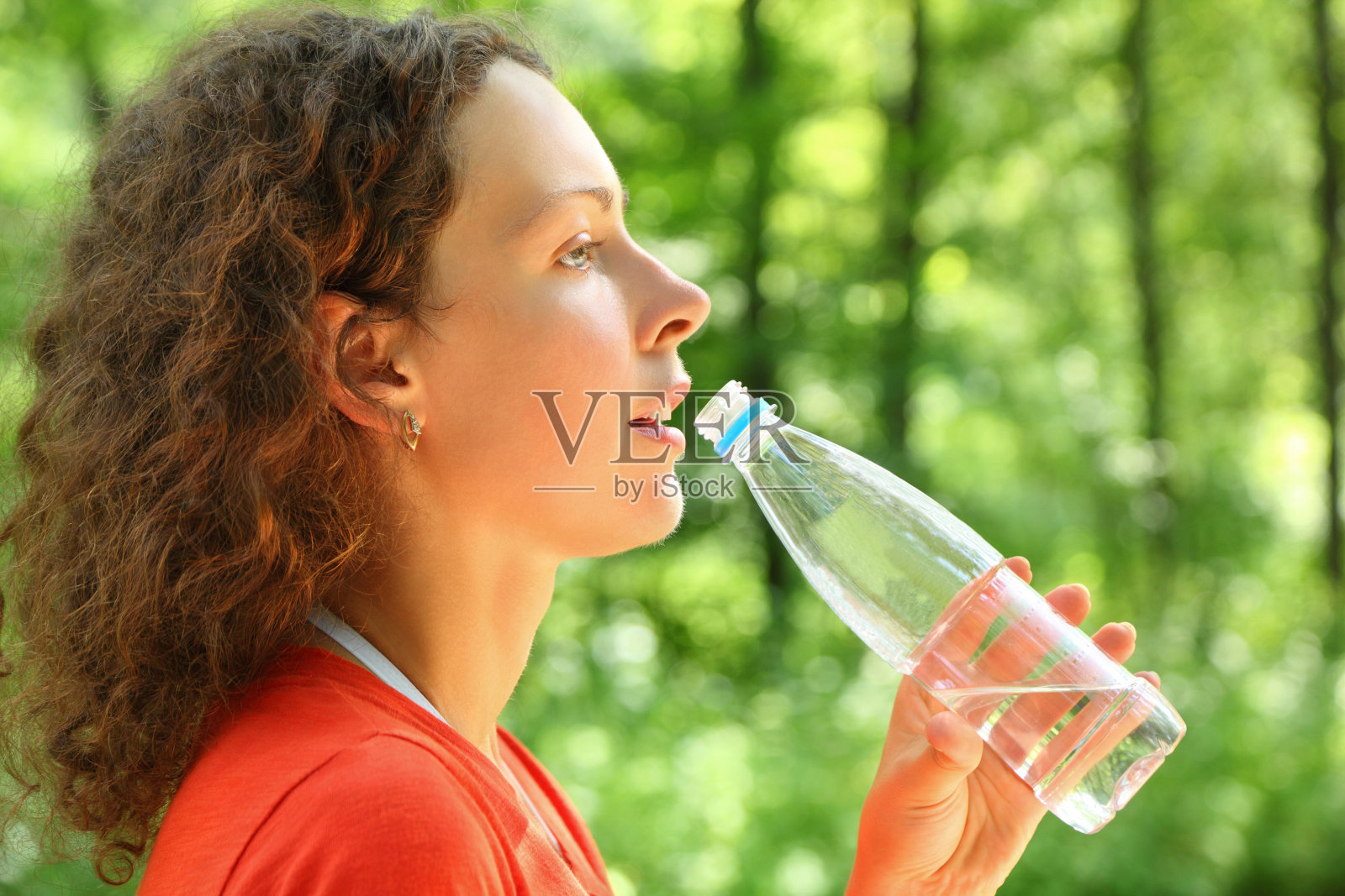 女人从瓶子里喝水，眼睛朝前看照片摄影图片