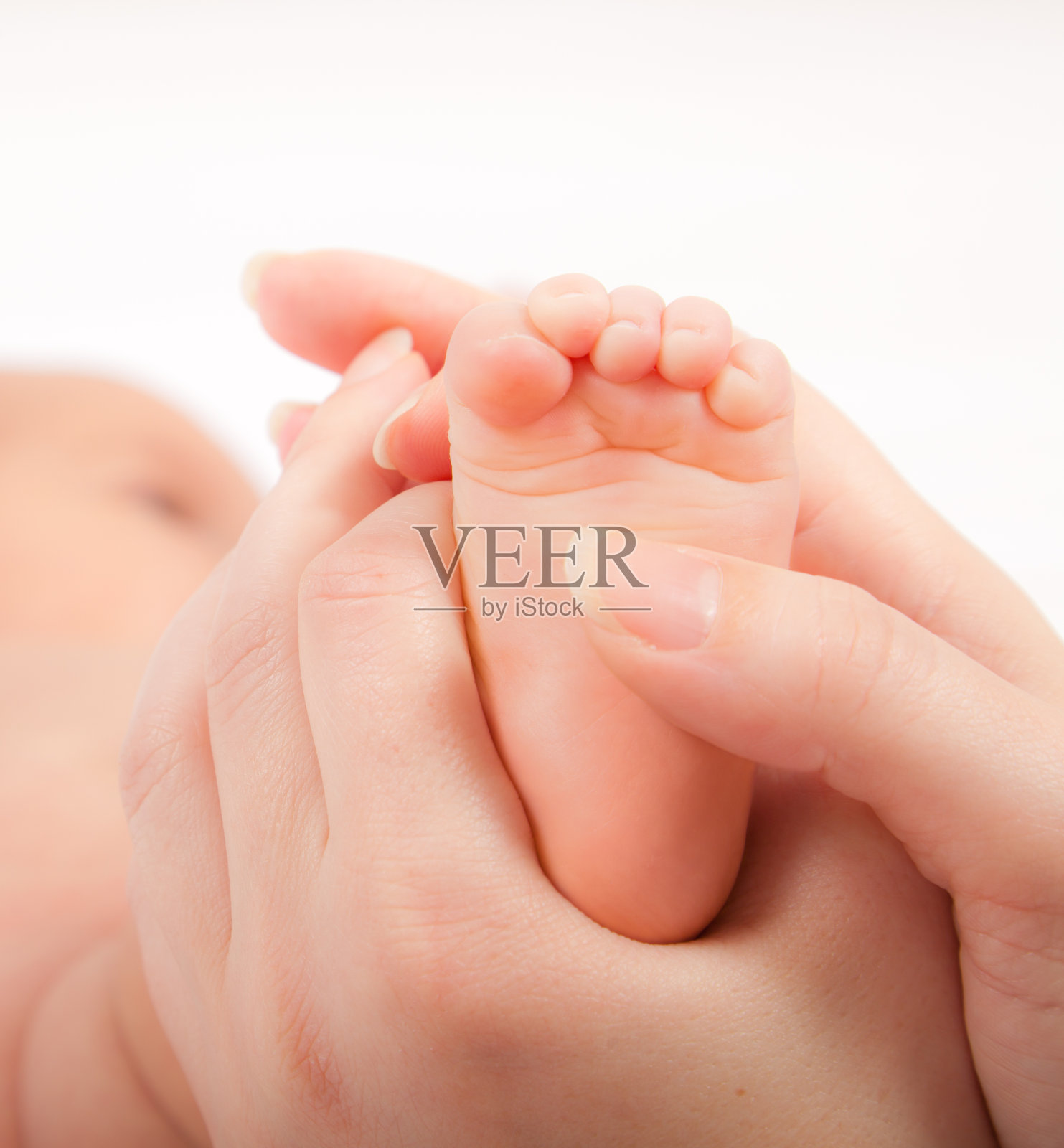 女人用手按摩小婴儿的脚，近处照片摄影图片