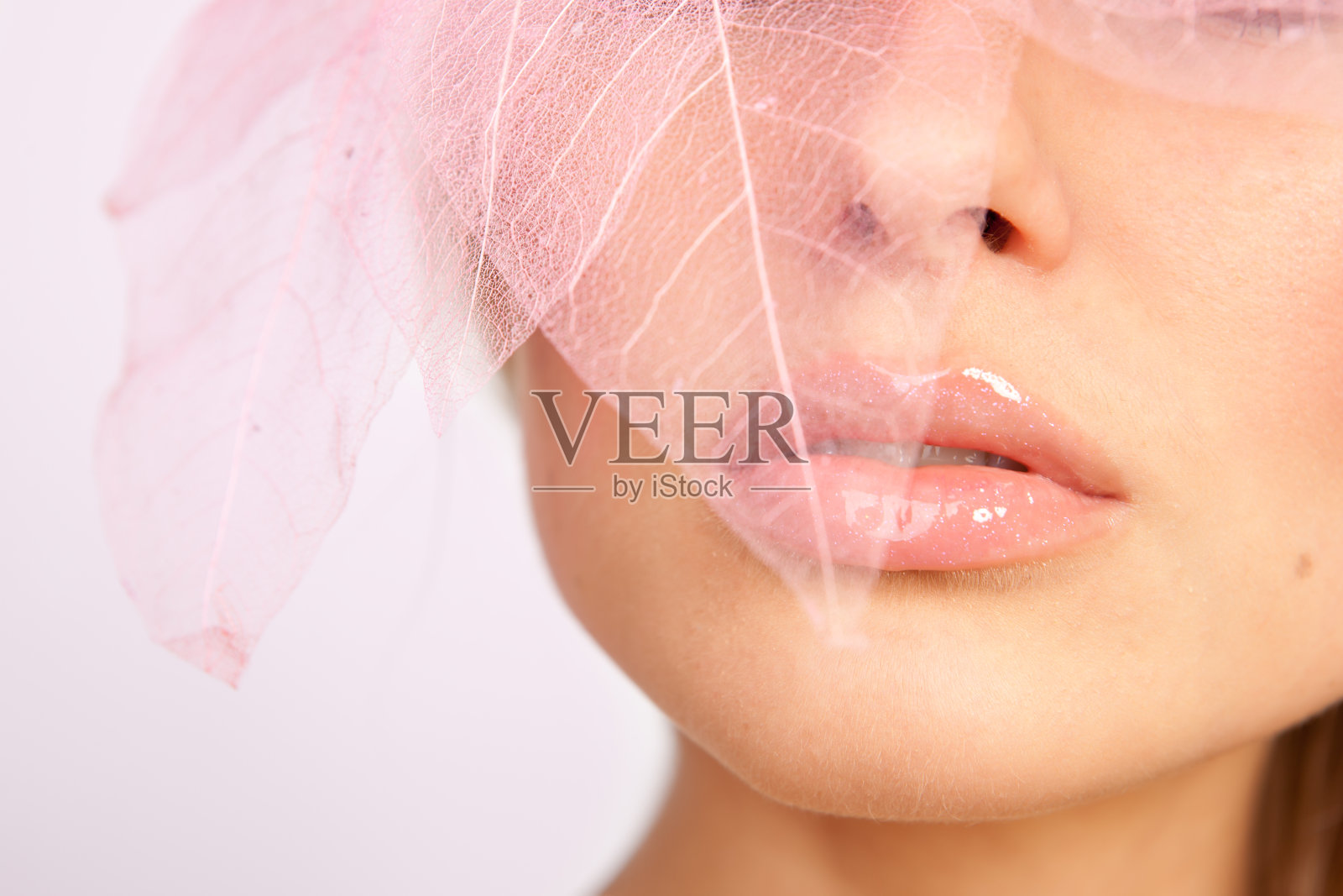 特写美丽的脸与粉红色的嘴唇，装饰树叶照片摄影图片