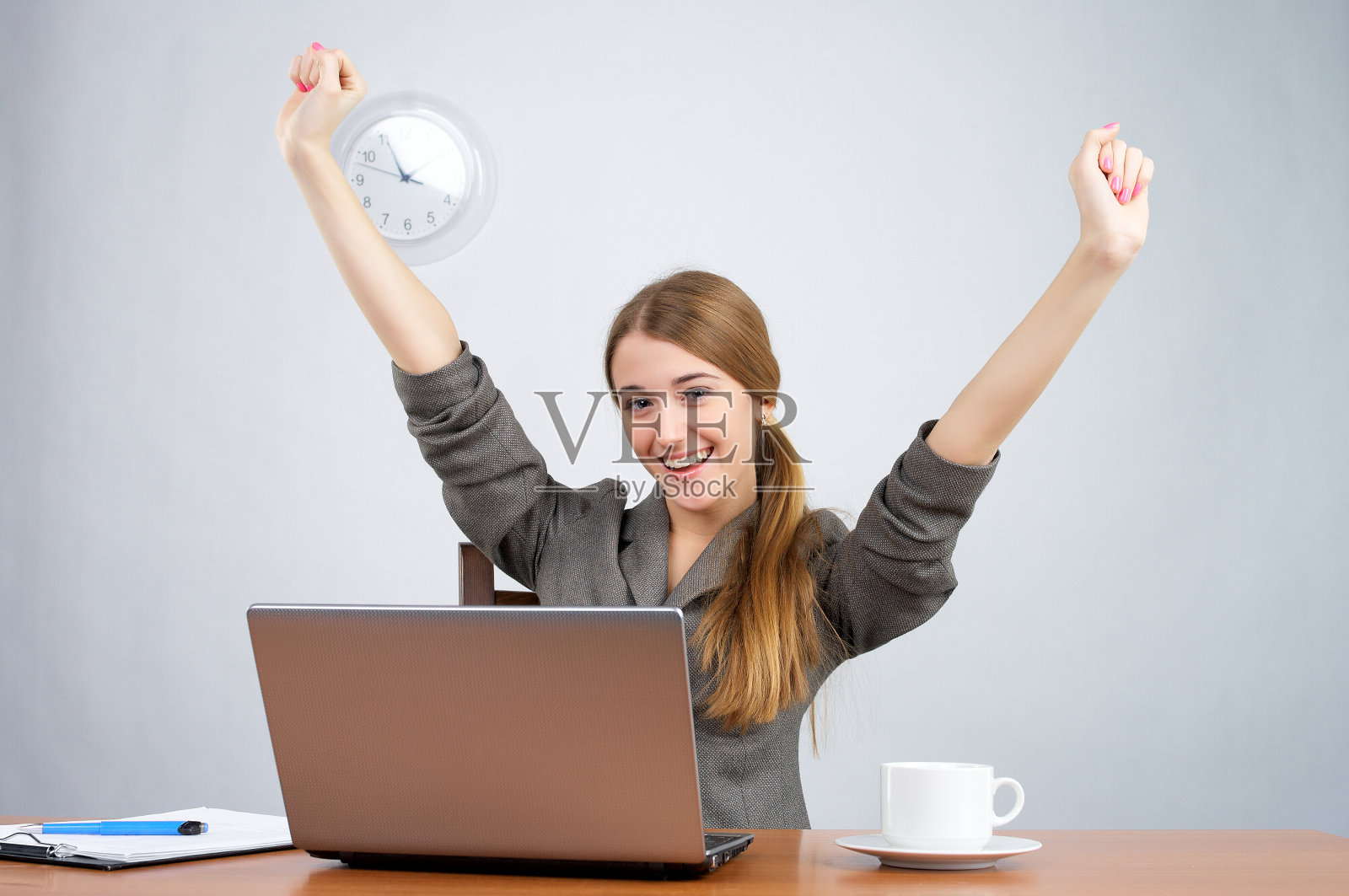 带着胜利的臂膀坐在办公桌前的女商人照片摄影图片