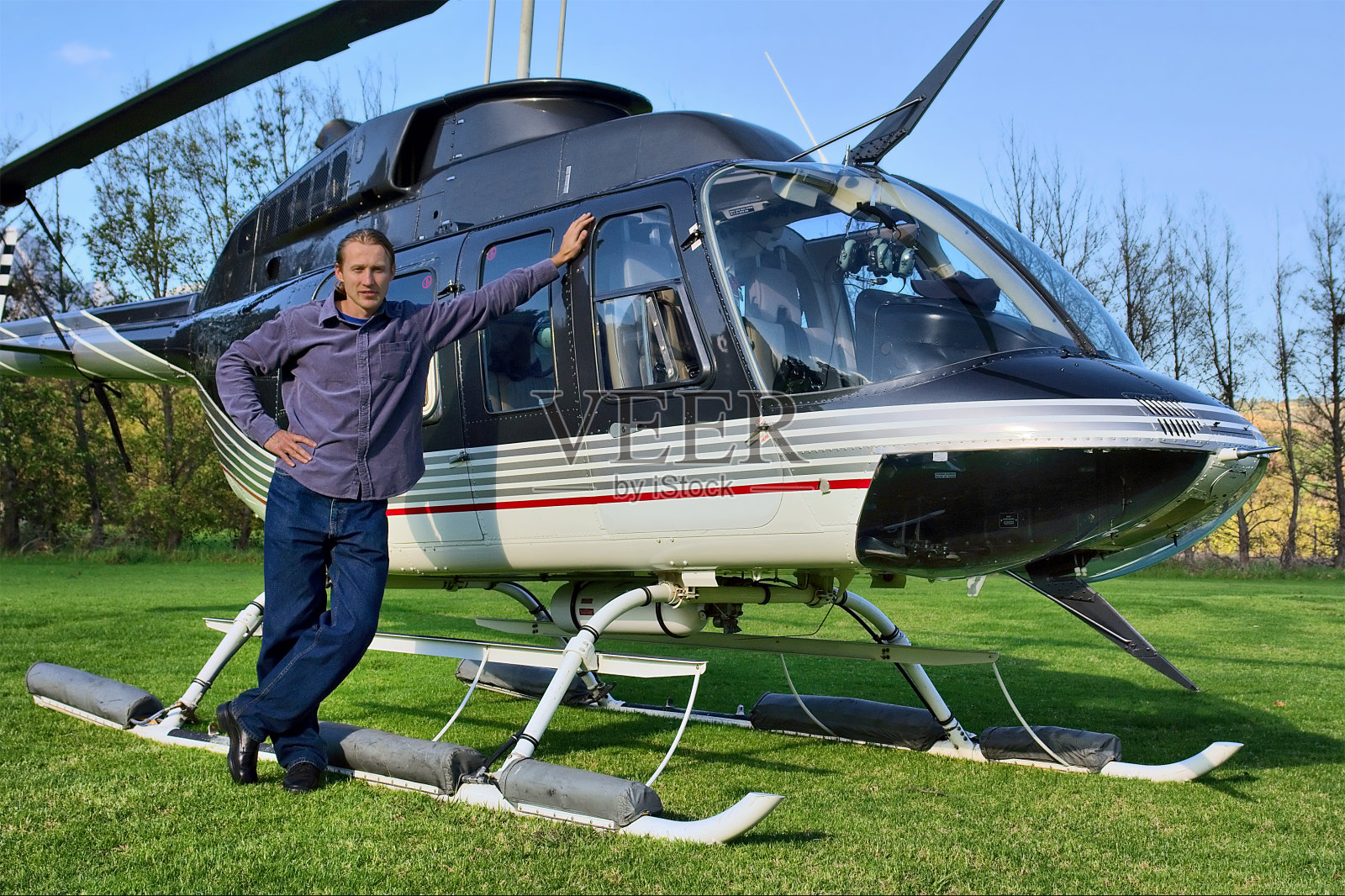 一个年轻人站在一架小型直升机旁照片摄影图片