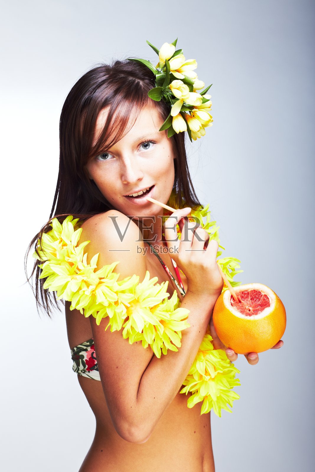 美丽的异国情调的女孩与夏威夷配件喝葡萄柚汁照片摄影图片