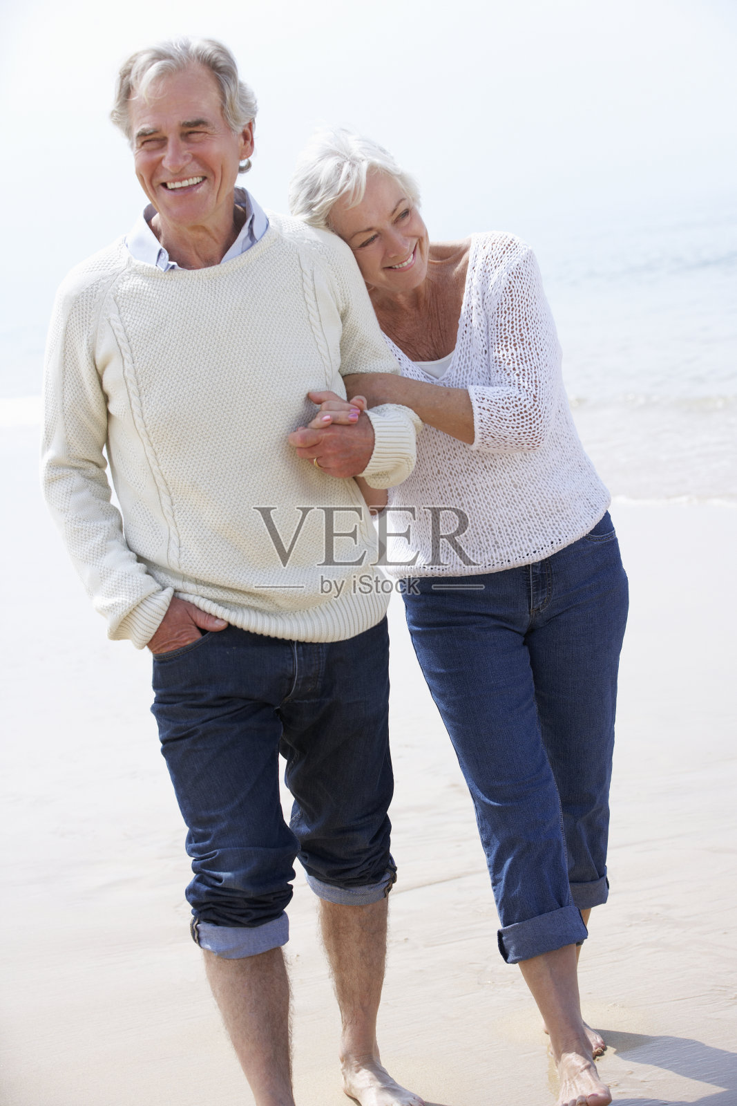 一对老年夫妇在海滩上手挽手散步照片摄影图片