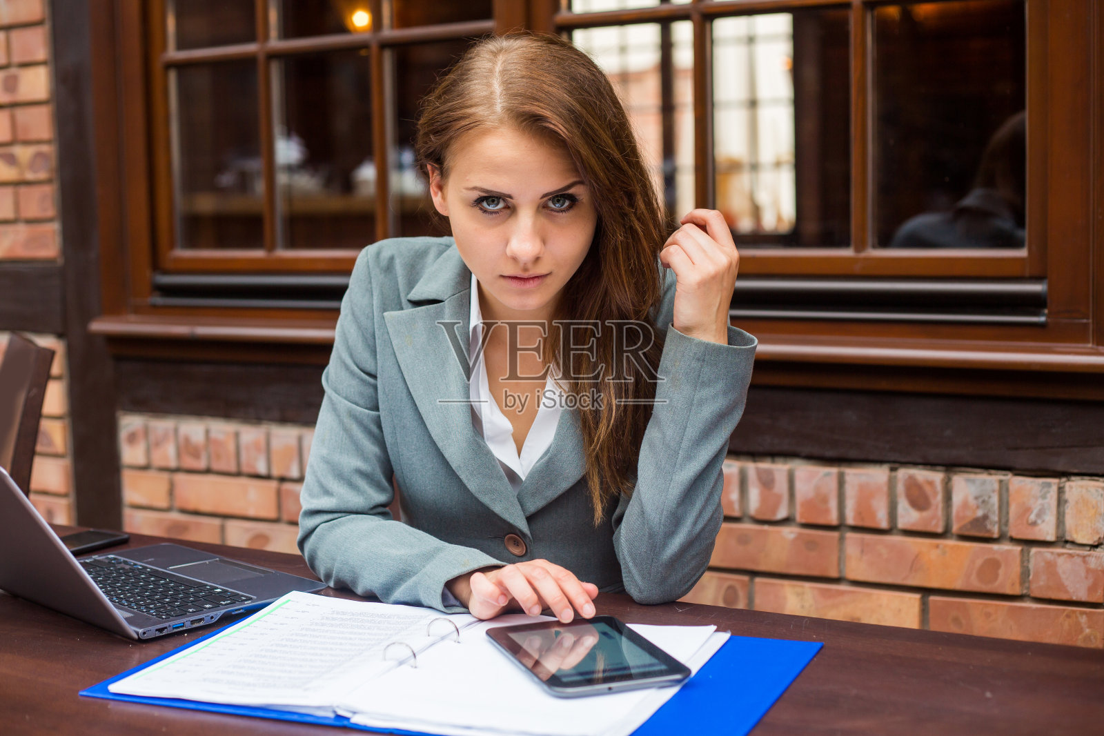 在餐厅里用笔记本电脑和笔记本工作的女商人。照片摄影图片