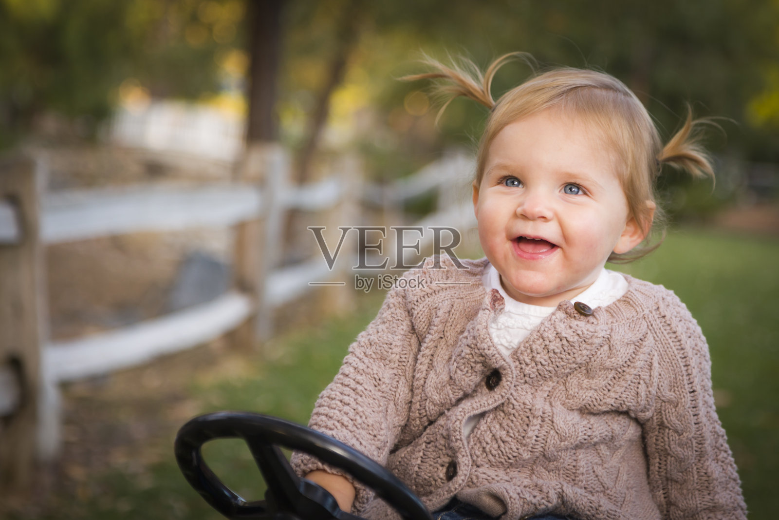 蹒跚学步的小孩在外面玩玩具拖拉机照片摄影图片