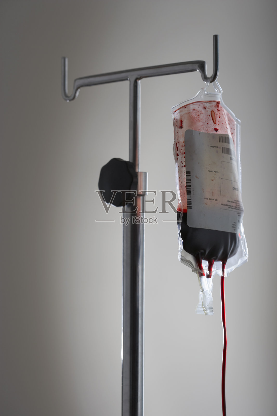 在白色的背景下，支架上有血迹的点滴袋照片摄影图片