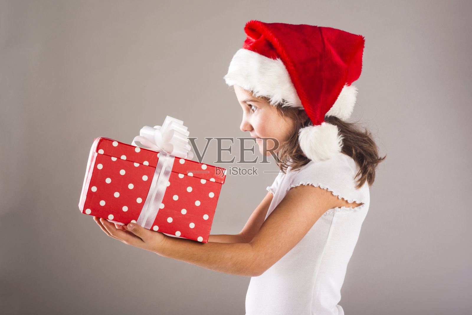 小女孩戴着圣诞帽，带着圣诞礼物照片摄影图片