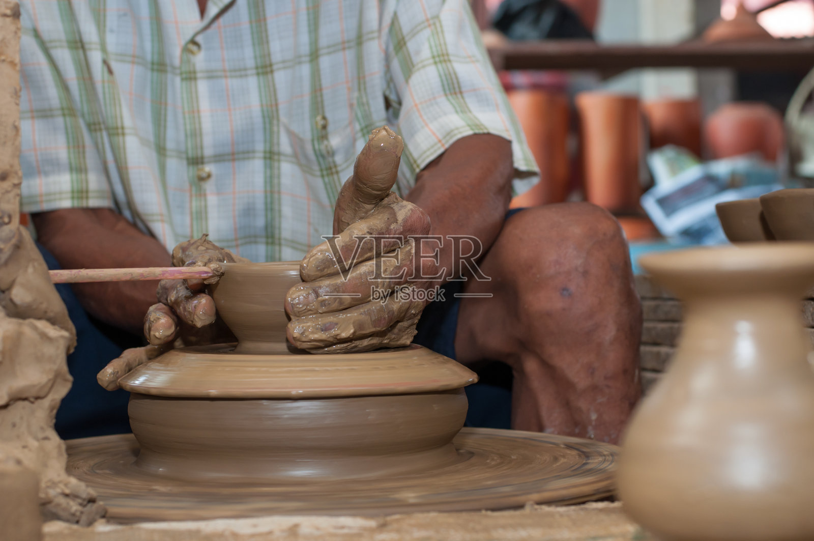 当陶器在轮子上转动时，人在塑造陶器照片摄影图片